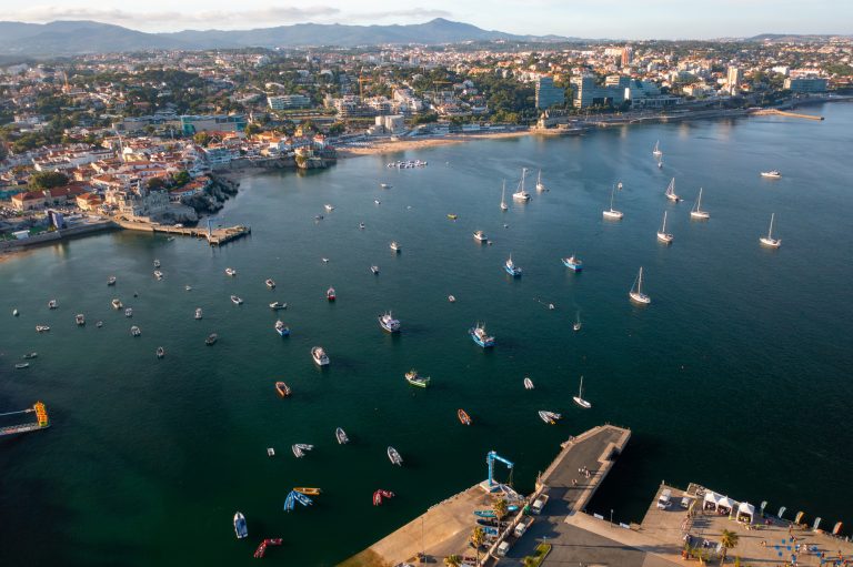 Drone panning above crowded cityscape and Cascais marina in Portugal
