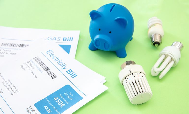 Electricity and gas bills, piggy bank, light bulb and heating thermostat.