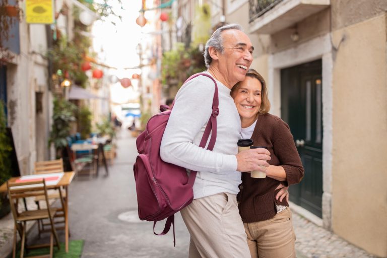 Happy Senior Couple Traveling Standing Hugging Outside, Holding Coffee Cups