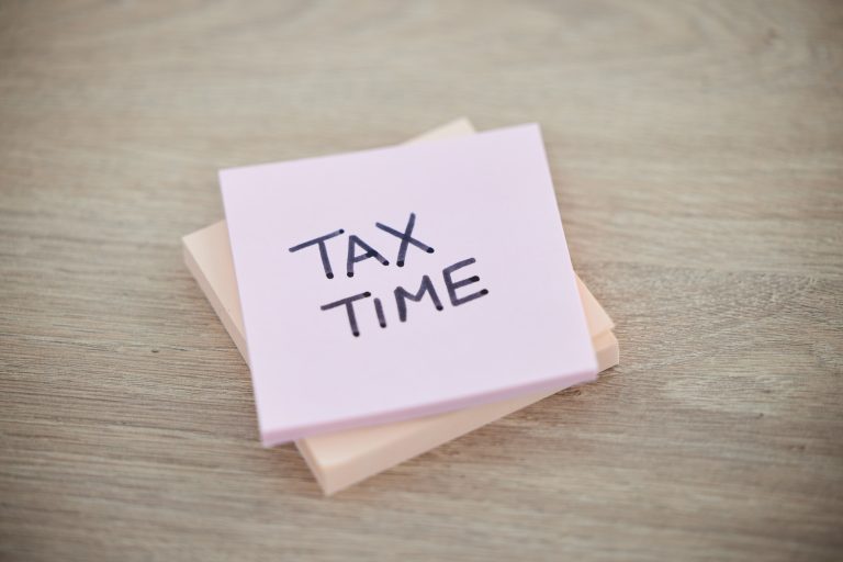 Tax, planning and sticky note with reminder for finance, audit and wealth on a desk. Accounting, pa